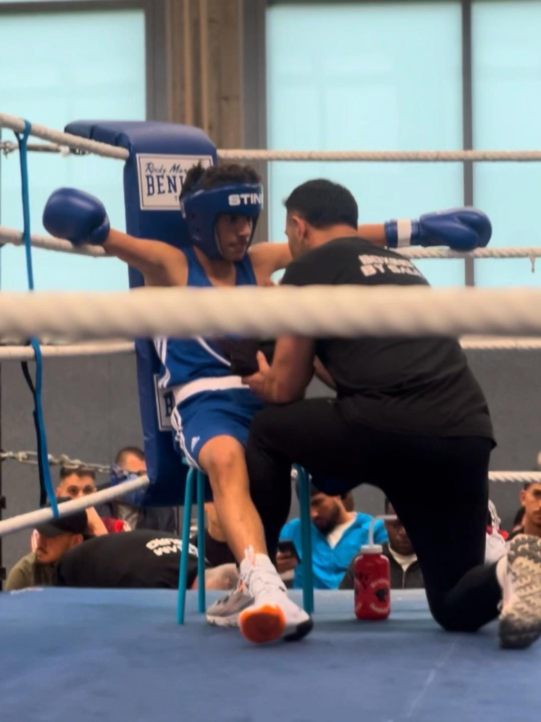 Mokitha Piyarathna in blue boxing kit receiving attention from his corner in the ring