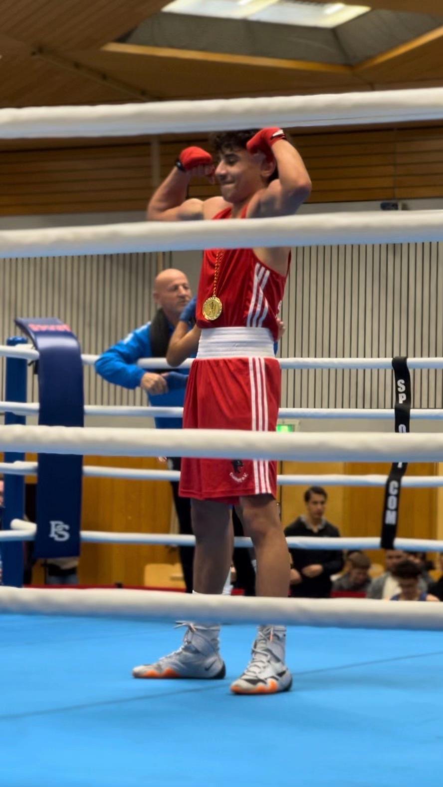 celebrating with a medal in red amateur boxing kit